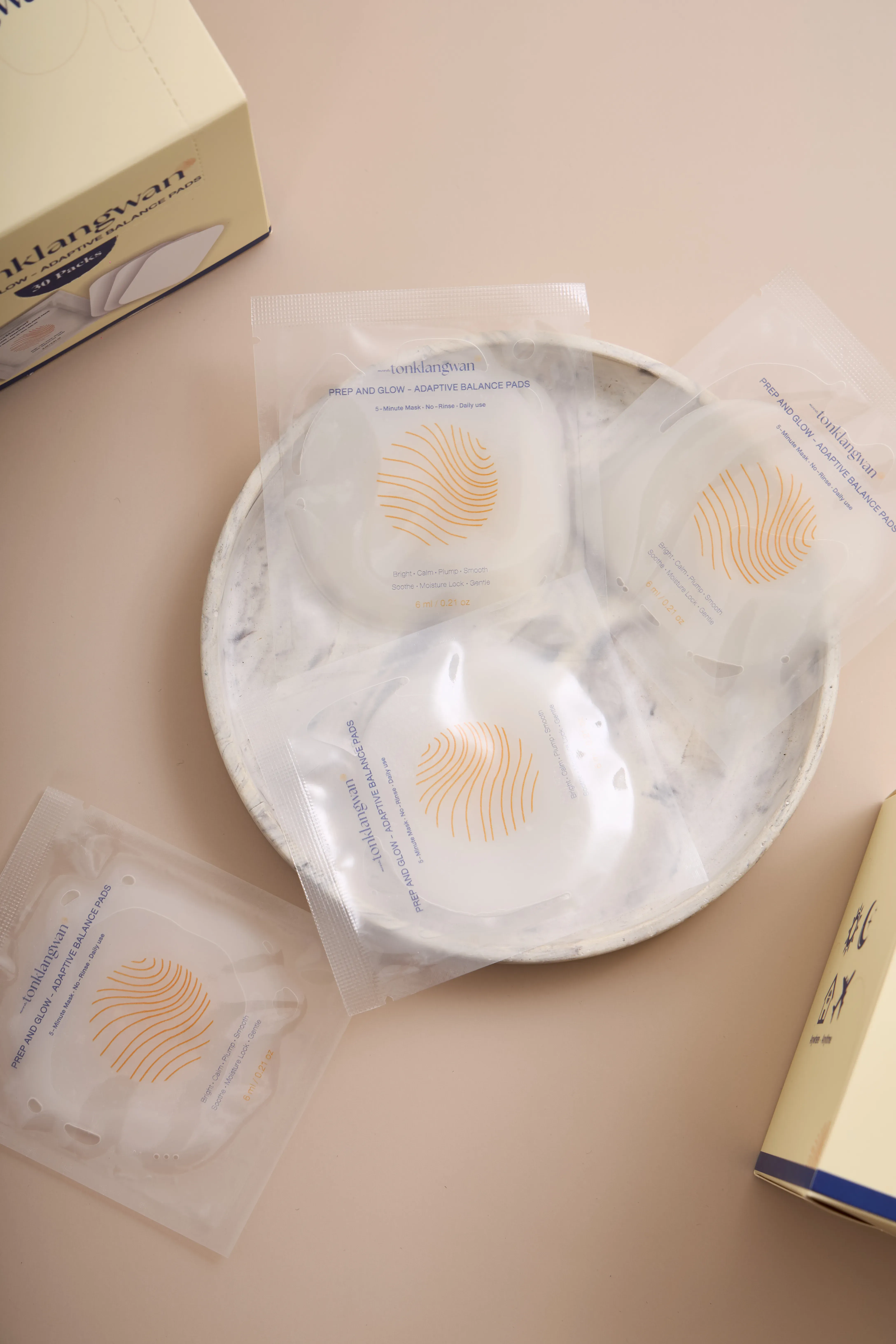 ซอง Prep and Glow Adaptive Pads บนจานหินอ่อน